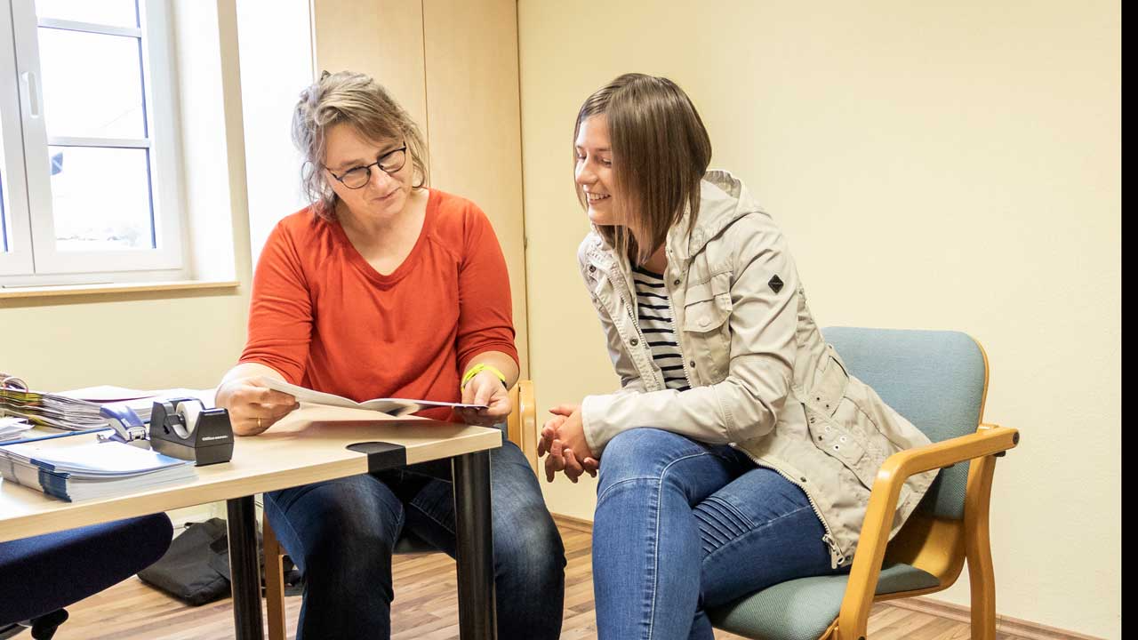 Beratungsgespräch mit Mutter, Kind und Fachkraft auf dem Sofa