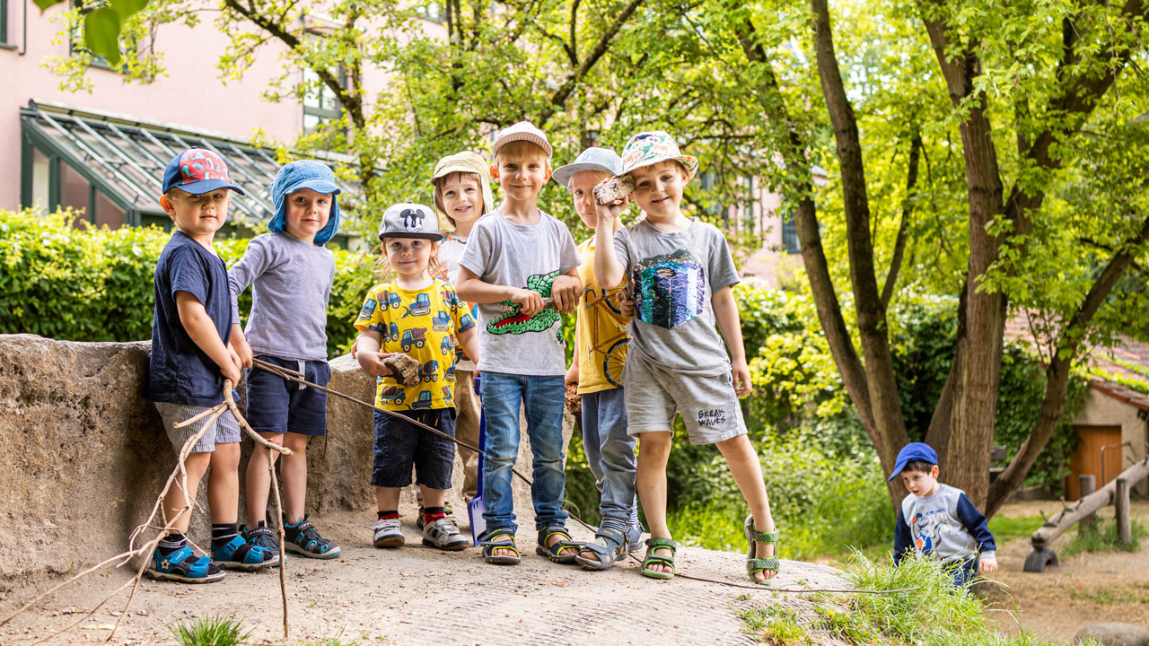 Kindergruppe mit Hüten im Garten der Einrichtung in Augsburg